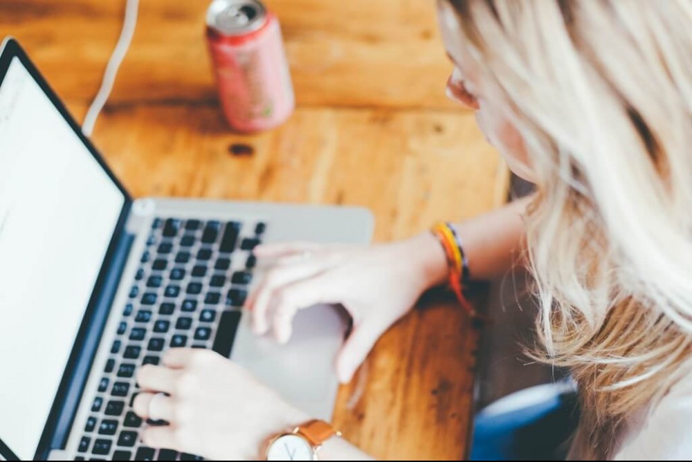 Lady typing on a laptop on a rustic wooden table